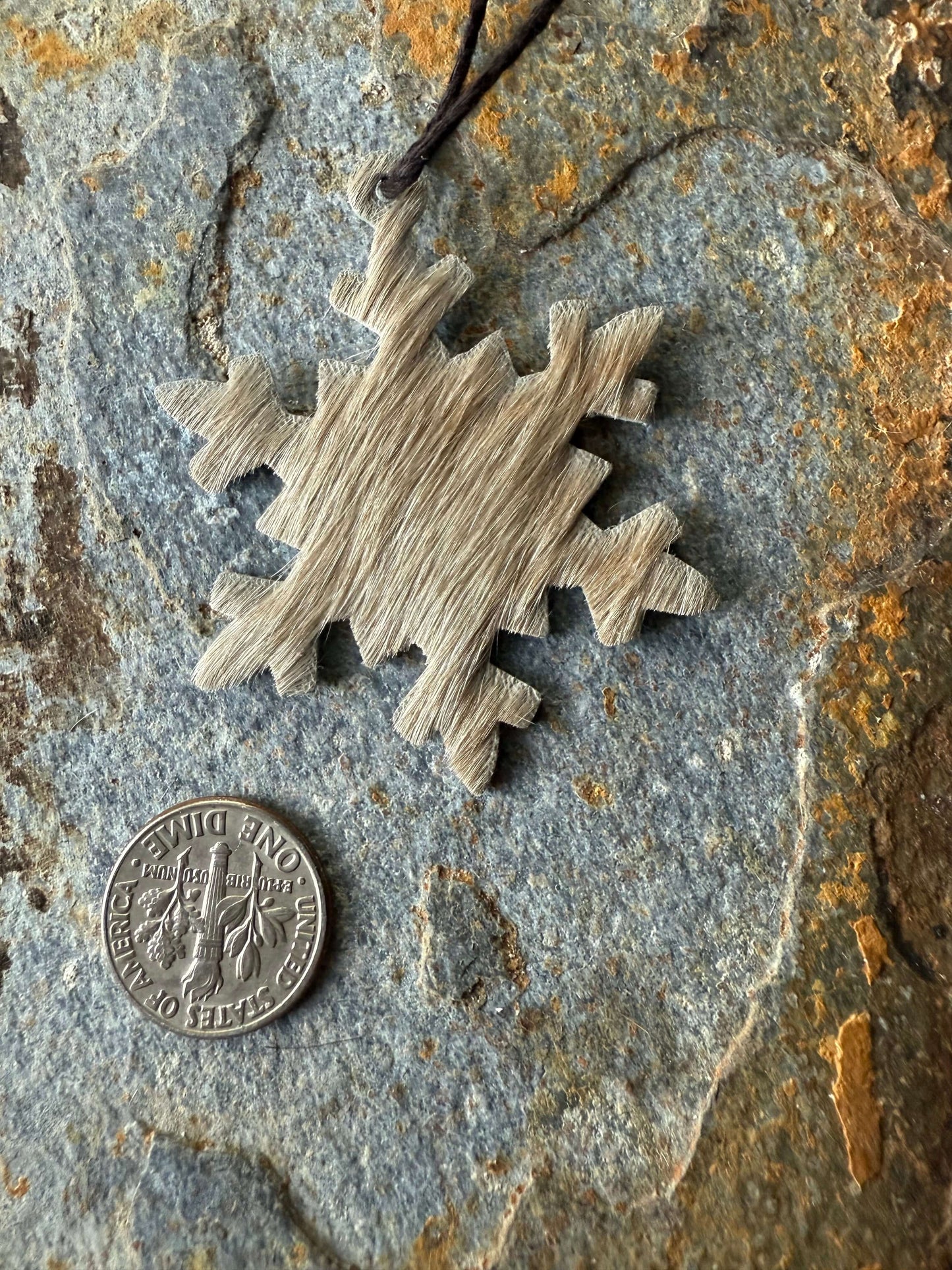 Hair on cowhide mini snowflake ornaments Hair on cowhide mini snowflake ornaments displayed beside a quarter for scale, showcasing unique texture.