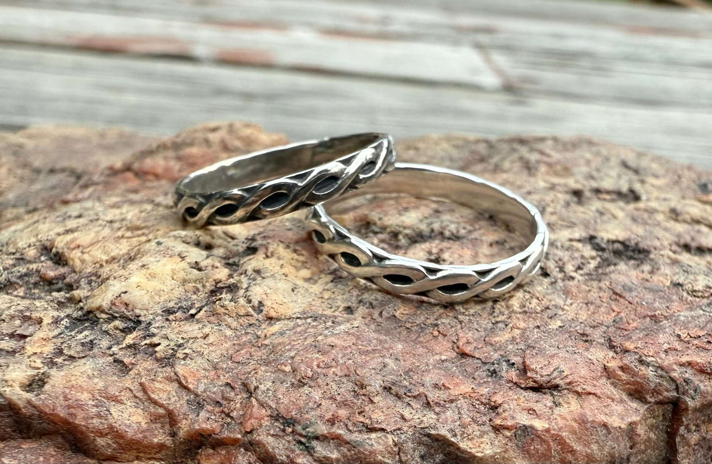 Two silver rings on a textured stone surface