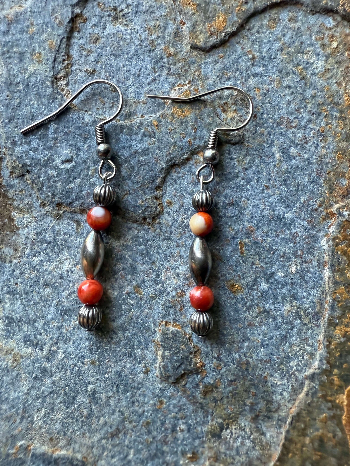 Sterling Silver Pearls & Red Spiny Oyster earrings showcasing vibrant red-orange stones on a rustic background.