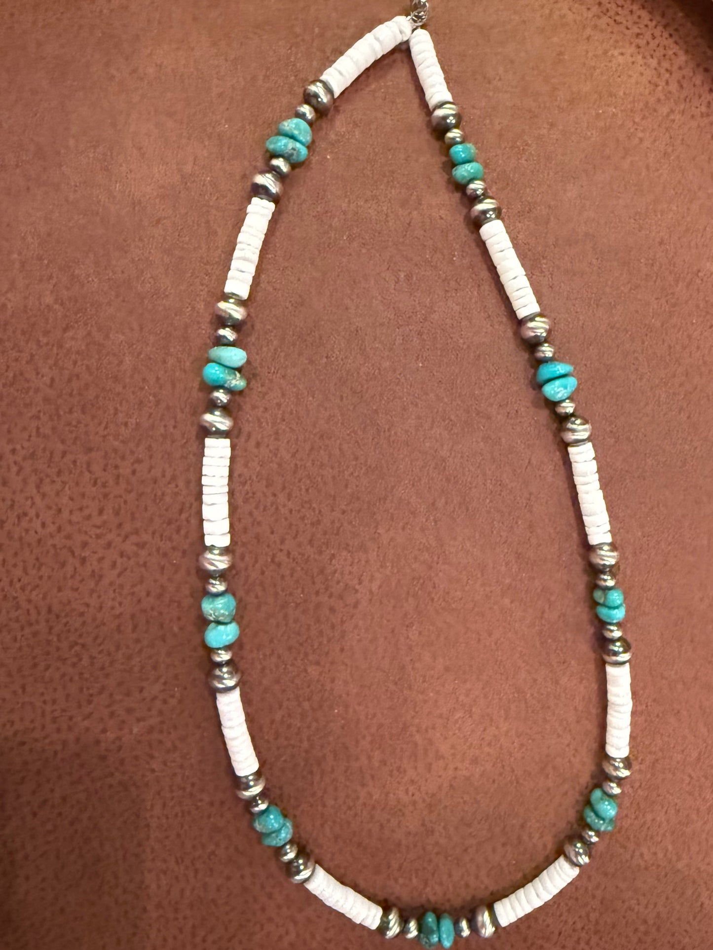 Necklace with turquoise and silver beads on a brown surface