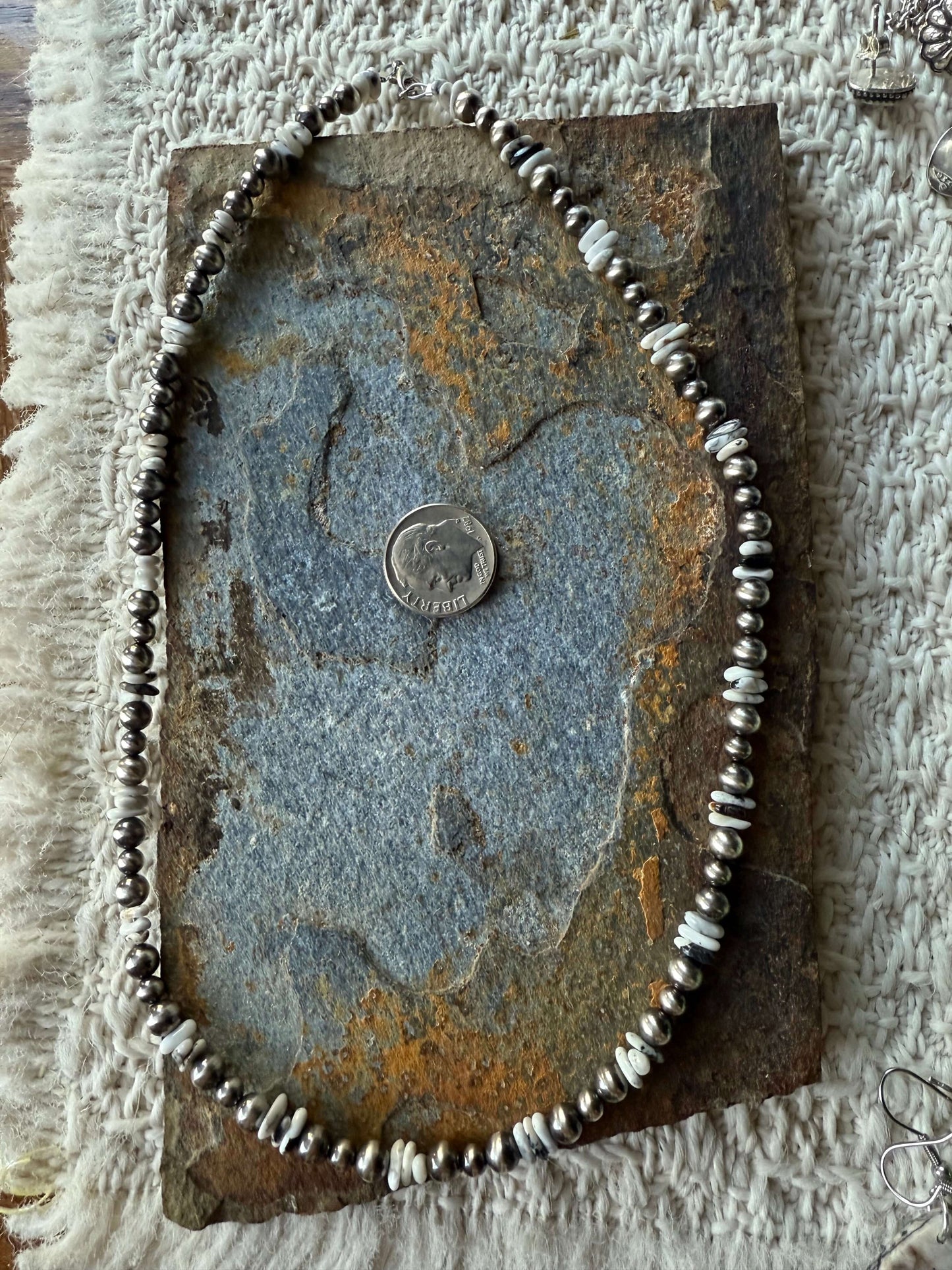 White Buffalo Chip Pearl Necklace displayed on rustic stone surface with a quarter for scale.