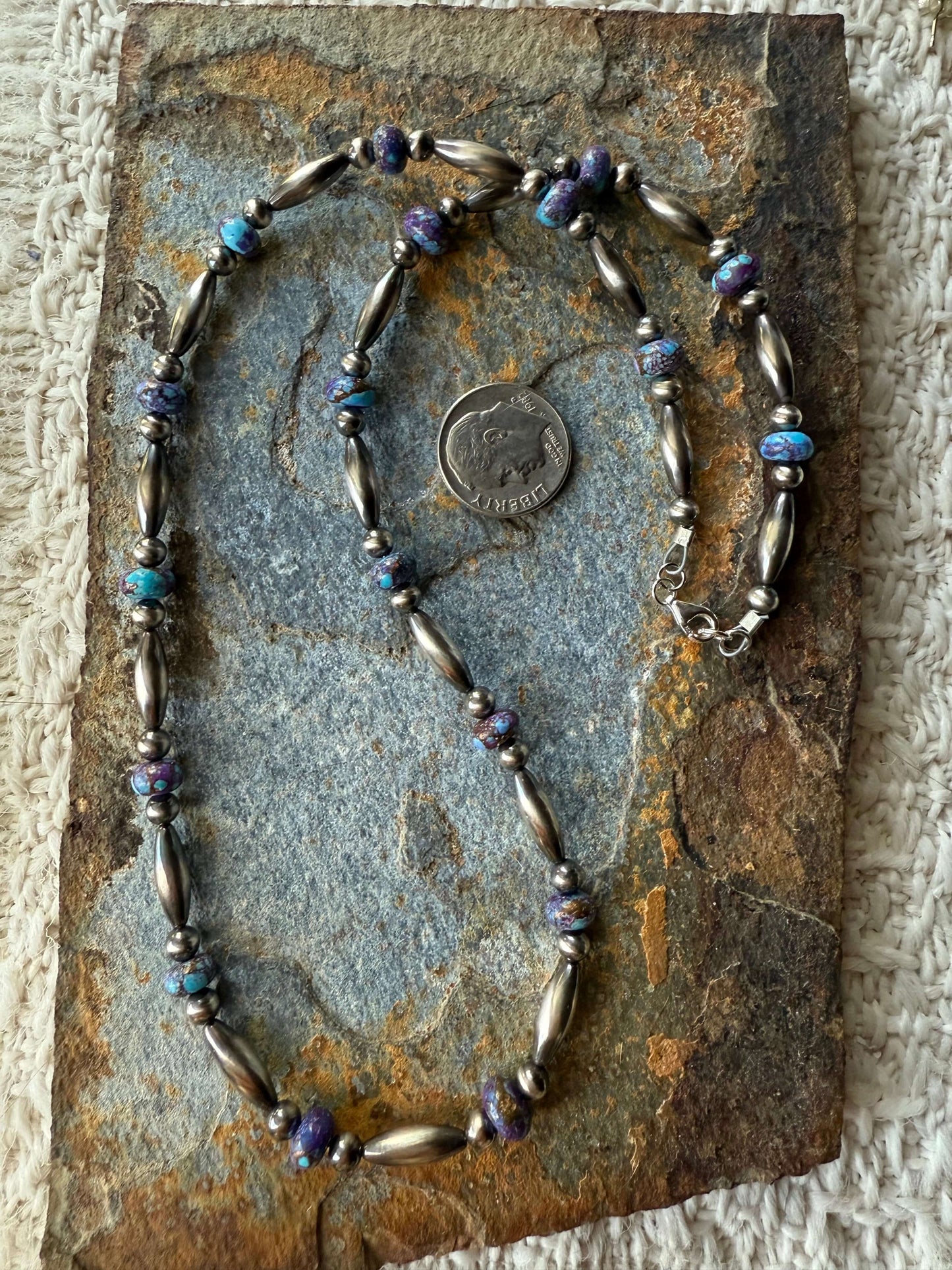 Purple Mohave Pearl Necklace displayed on a stone background with a quarter for scale.