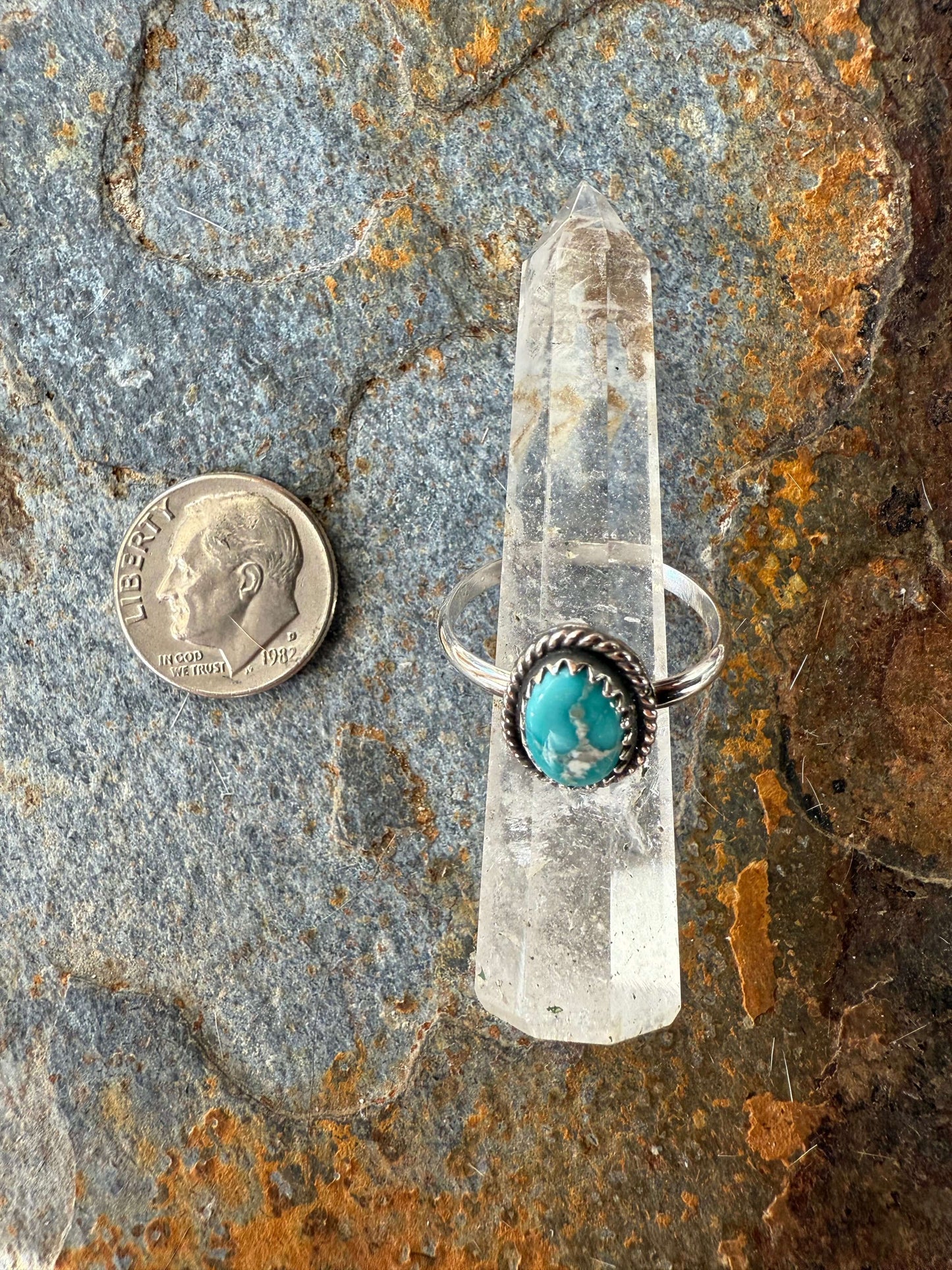 Focus Keyword Fox Turquoise Ring displayed on a crystal pedestal next to a quarter for size comparison.
