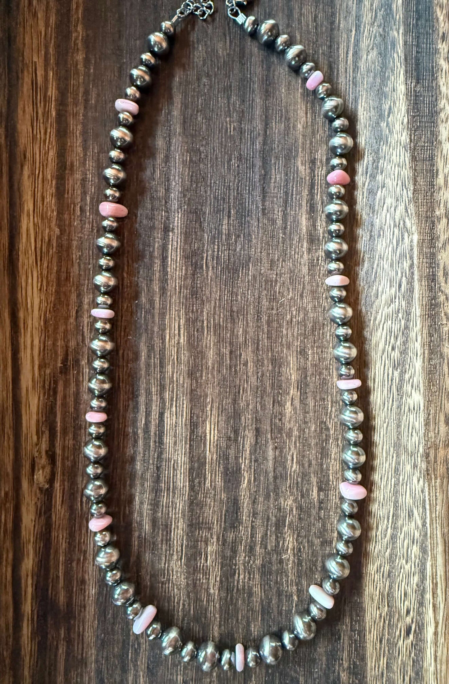 Pink Conch Shell Chip Sterling Silver Pearls Necklace 18 inch on a wooden background.