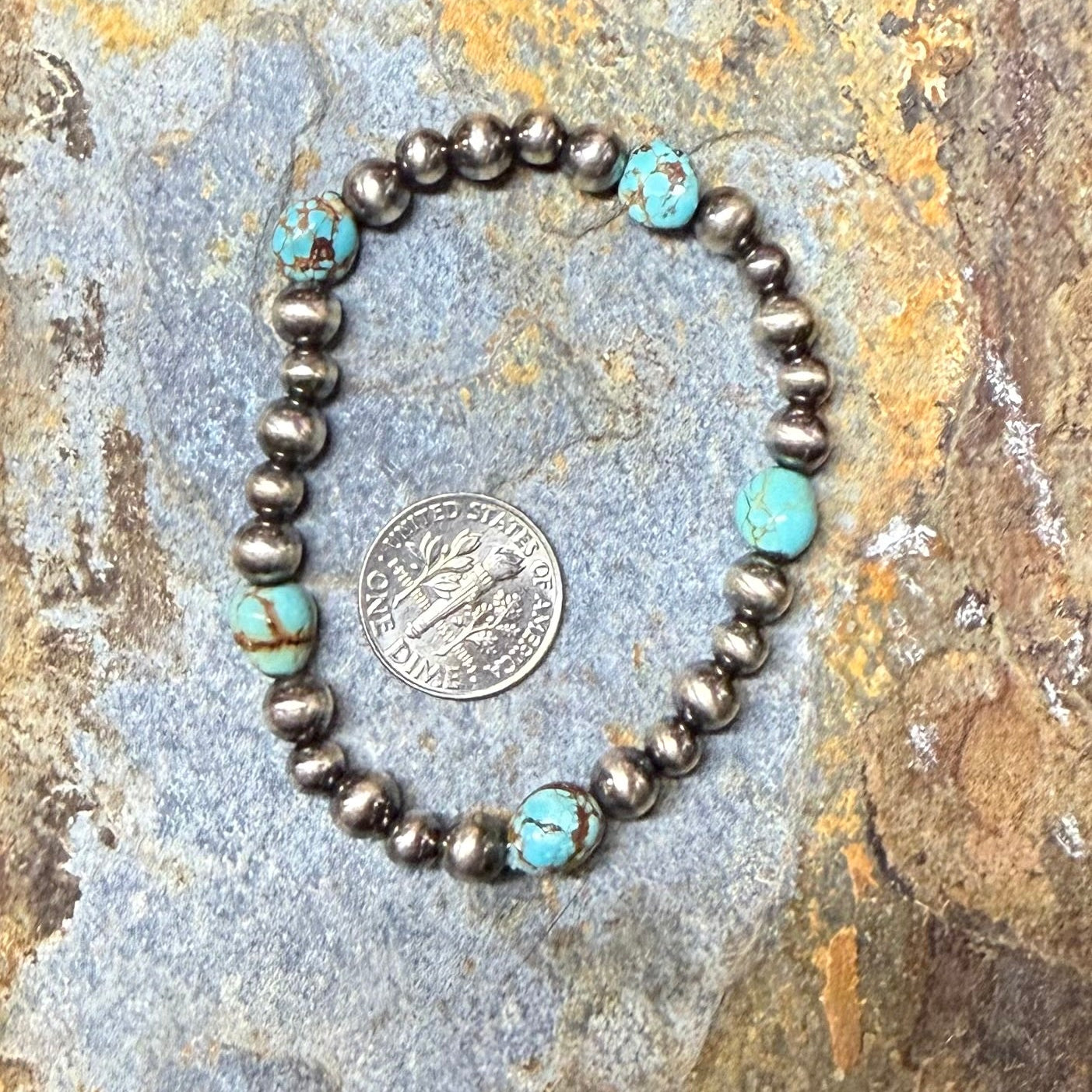 Bracelet with turquoise and silver beads on a stone surface