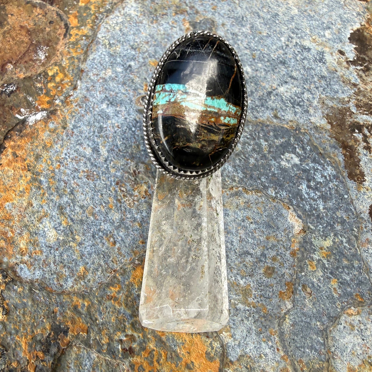BLACK STONE with a central crystal on a textured rock background
