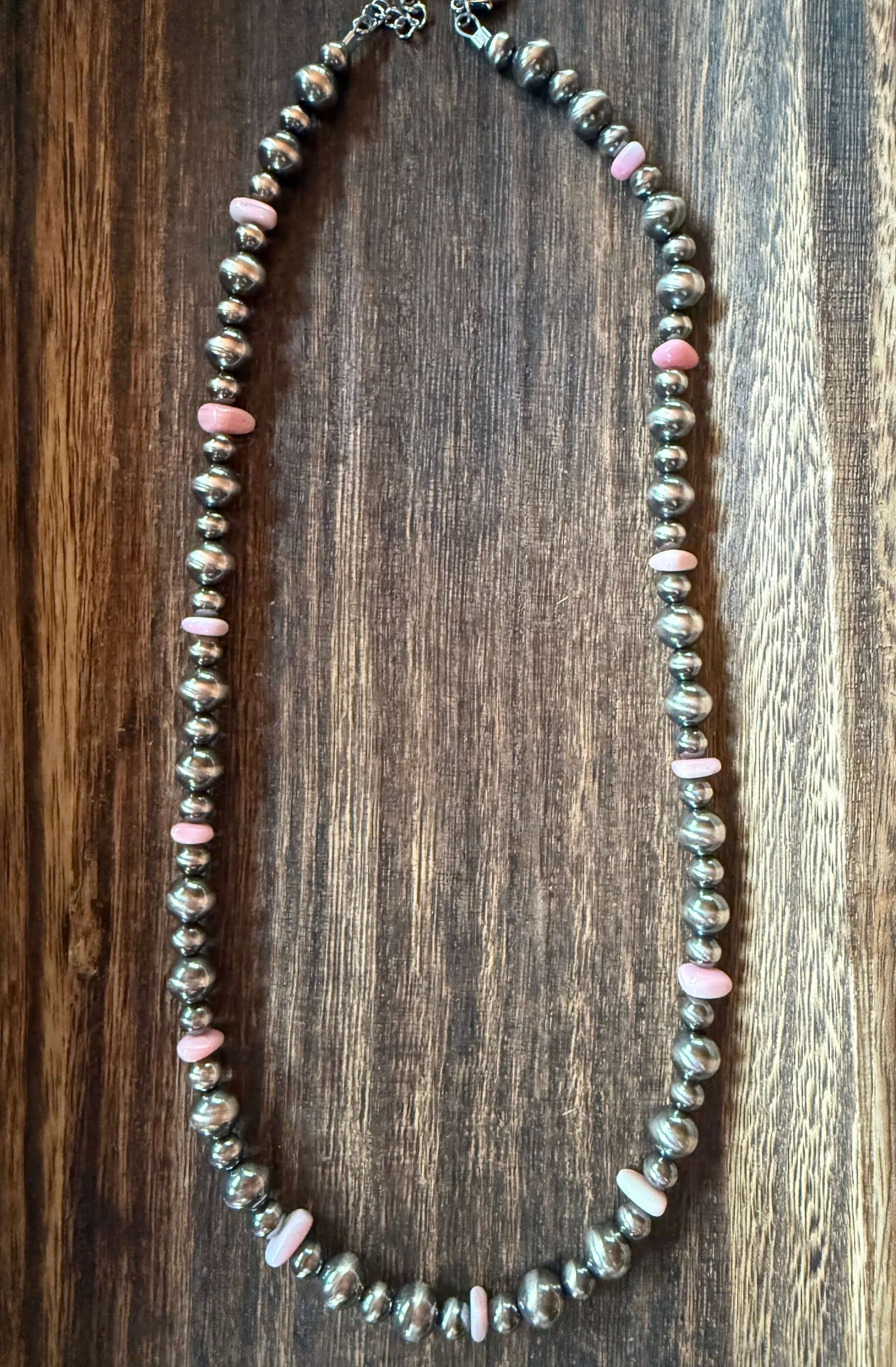 Pink Conch Shell Chip Sterling Silver Pearls Necklace 18 inch on a wooden background.