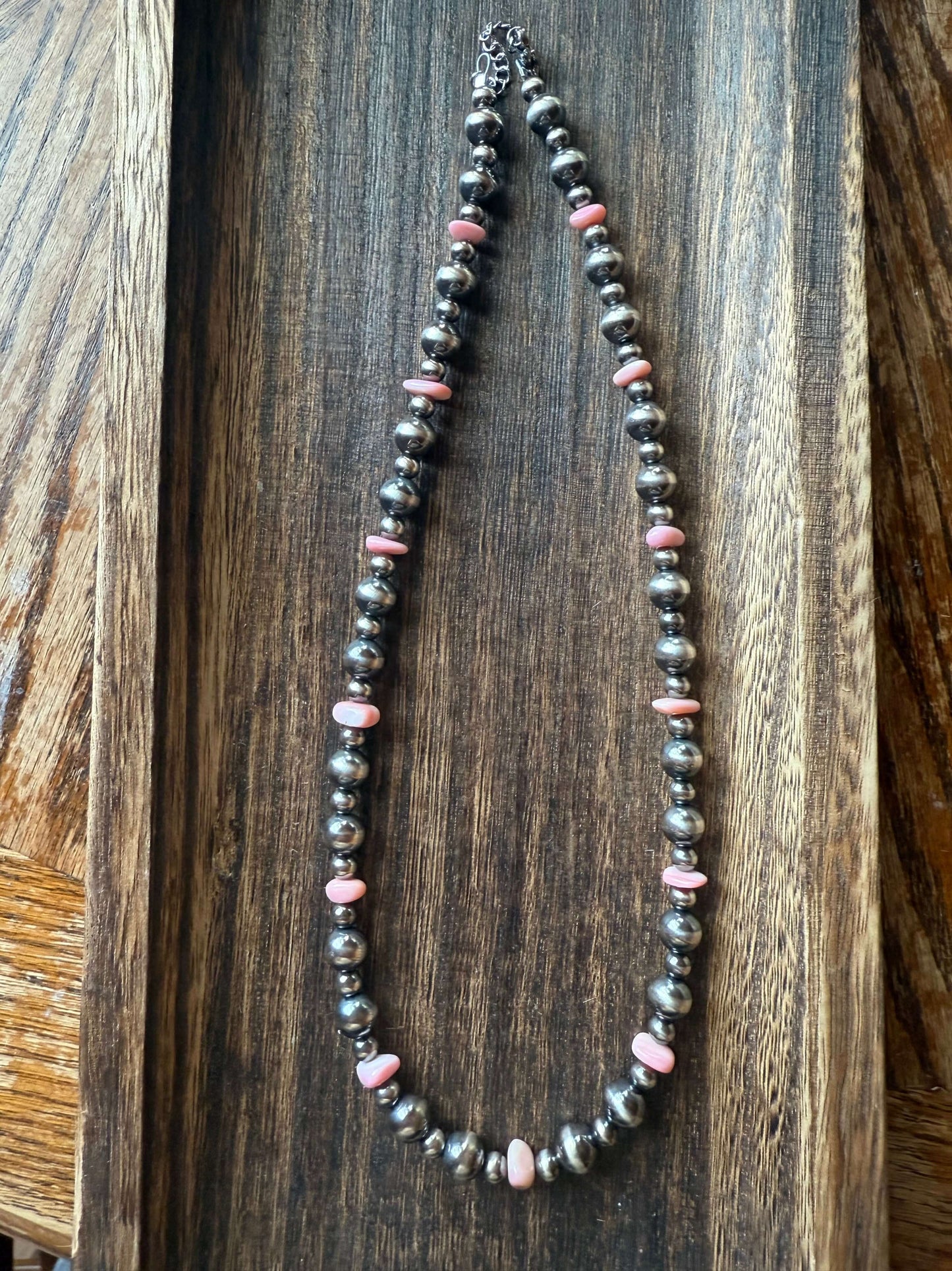 Pink Conch Shell Chip Sterling Silver Pearls Necklace 16 displayed on a wooden serving tray.