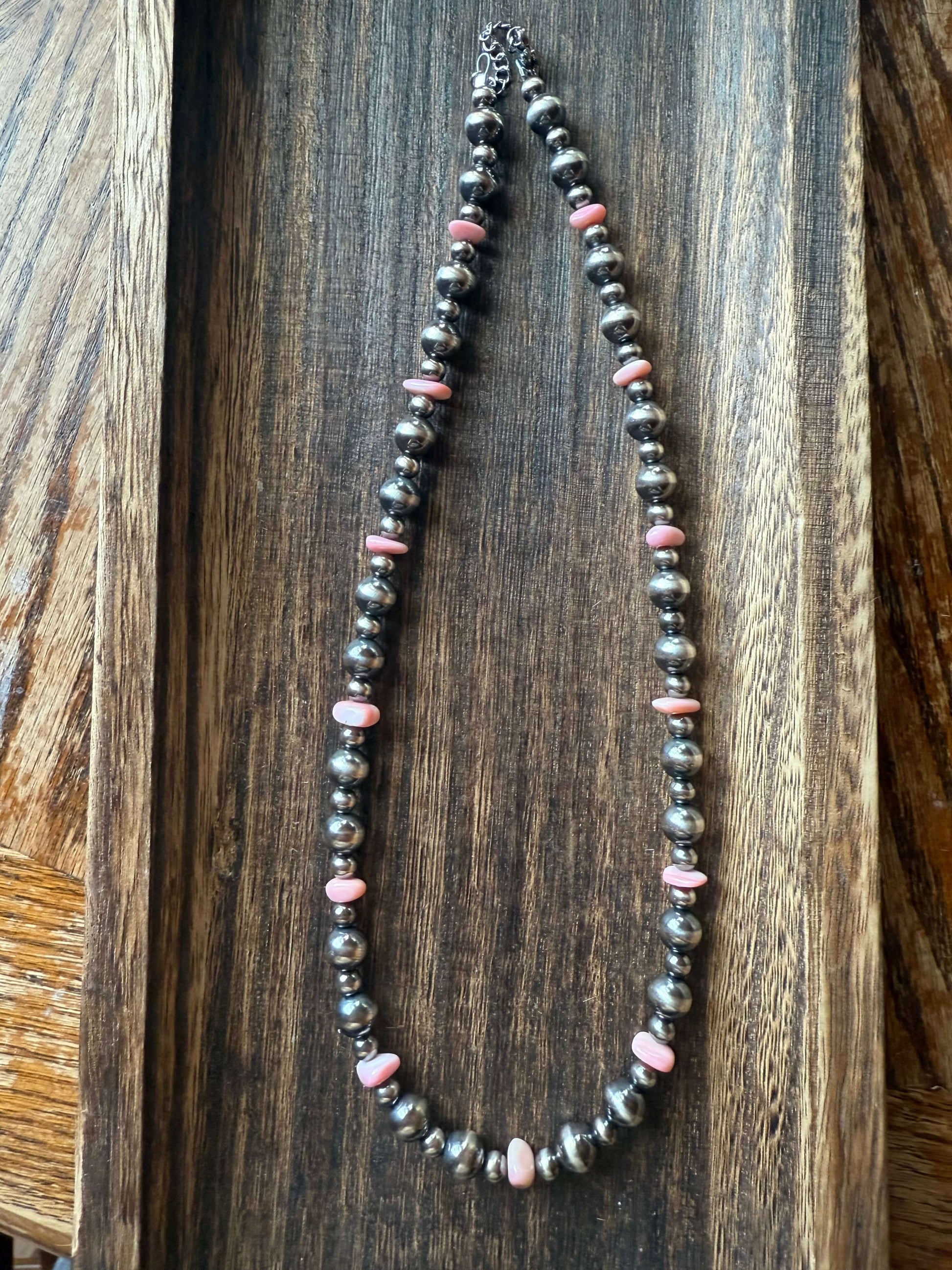 Pink Conch Shell Chip Sterling Silver Pearls Necklace 16 displayed on a wooden serving tray.