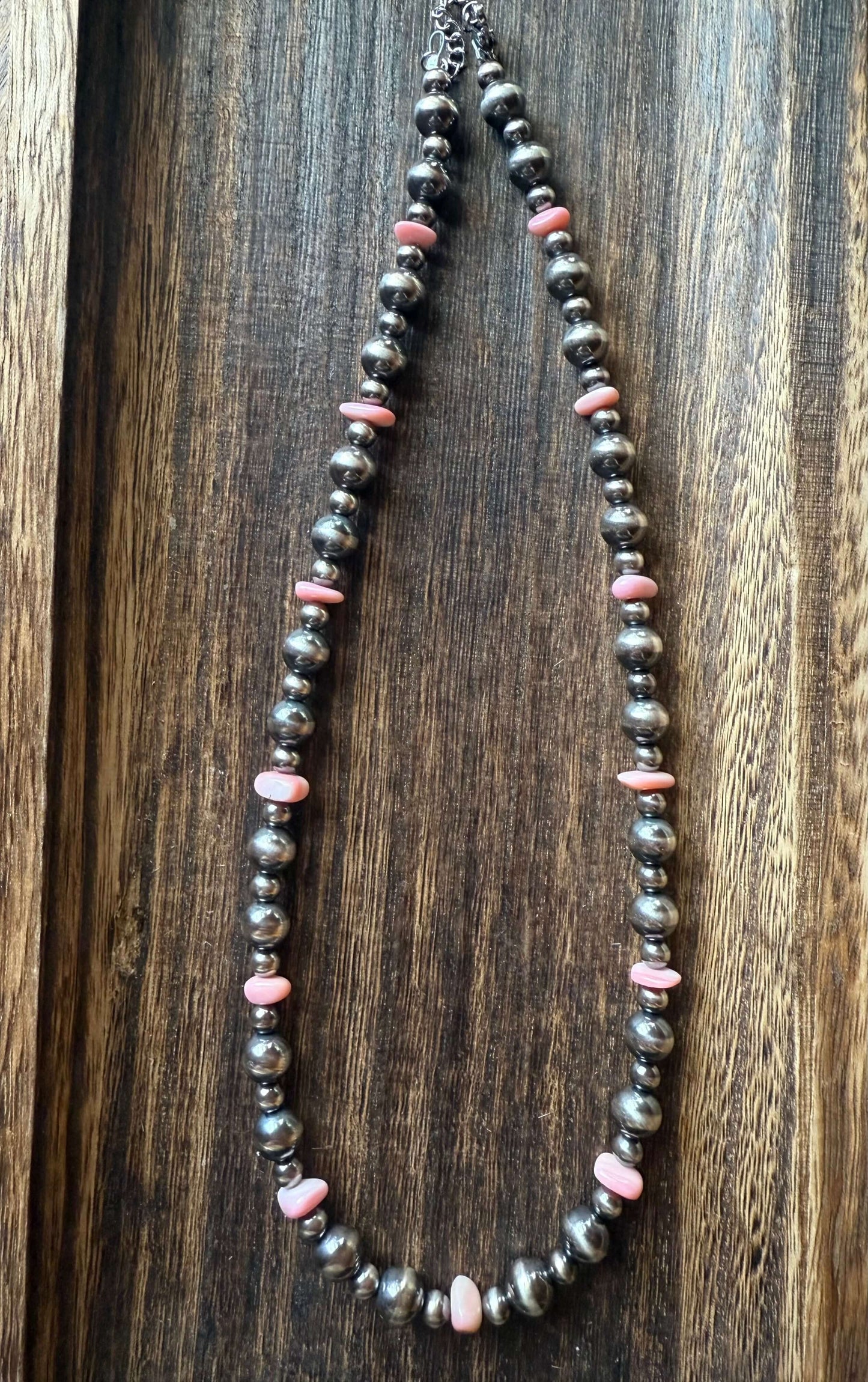 Pink Conch Shell Chip Sterling Silver Pearls Necklace 16 displayed on a wooden surface, featuring pink conch shell chips and sterling silver pearls.