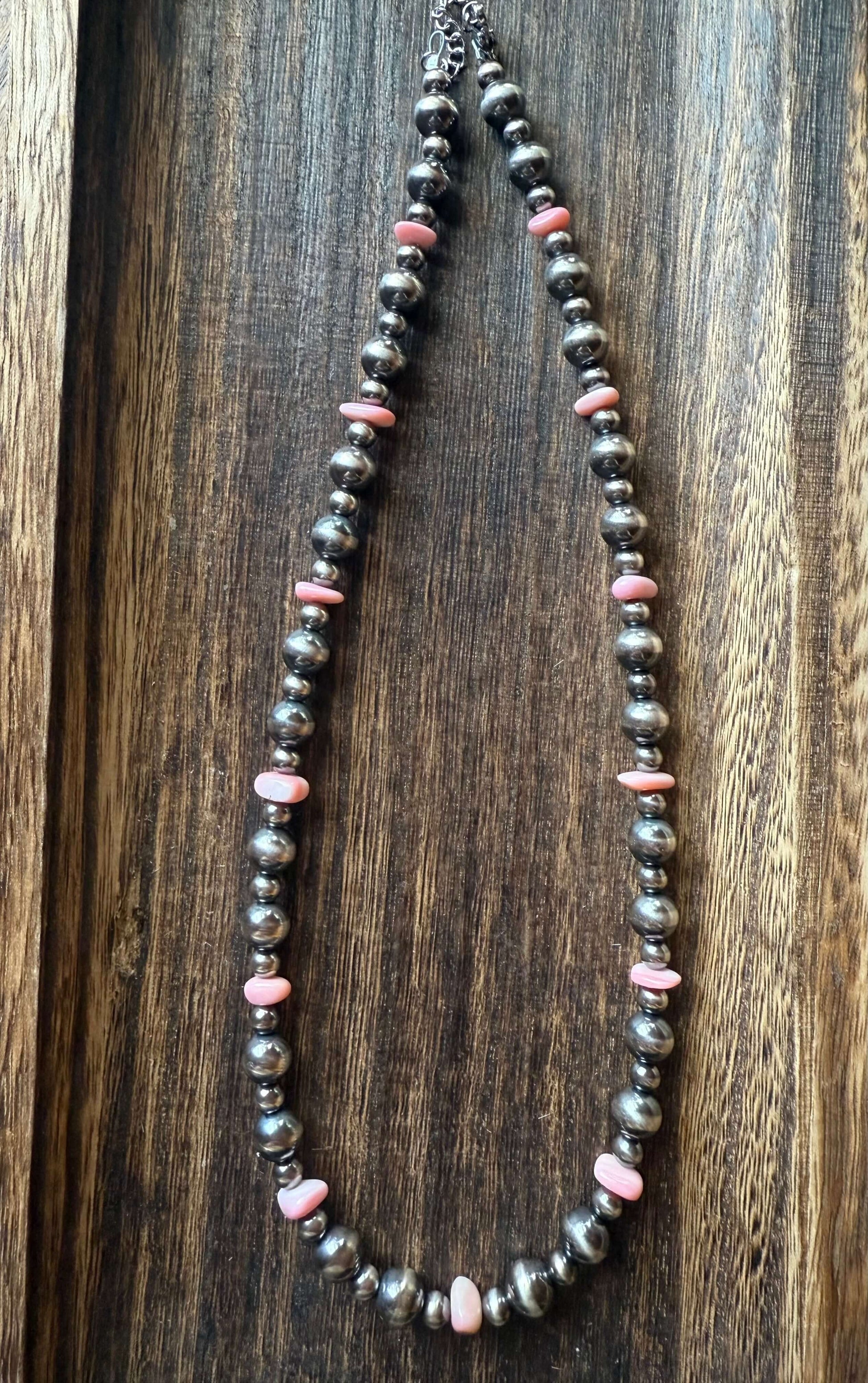 Pink Conch Shell Chip Sterling Silver Pearls Necklace 16 displayed on a wooden surface, featuring pink conch shell chips and sterling silver pearls.