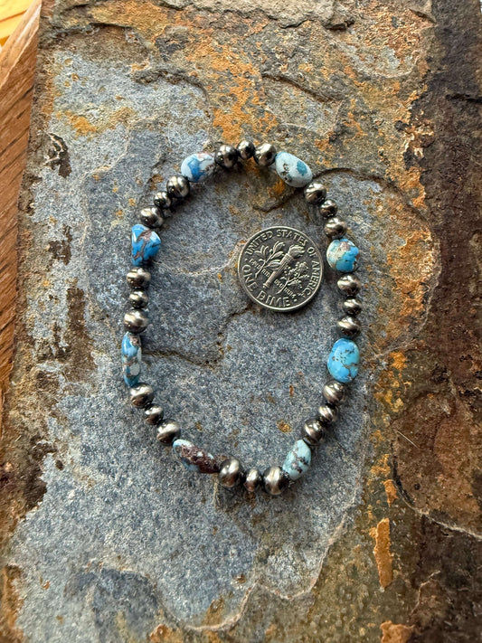 Golden Hills Turquoise Pearl Bracelet featuring blue turquoise stones and silver beads on a textured stone background.