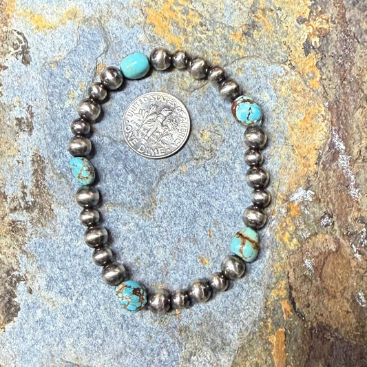Bracelet with turquoise and silver beads on a textured stone surface