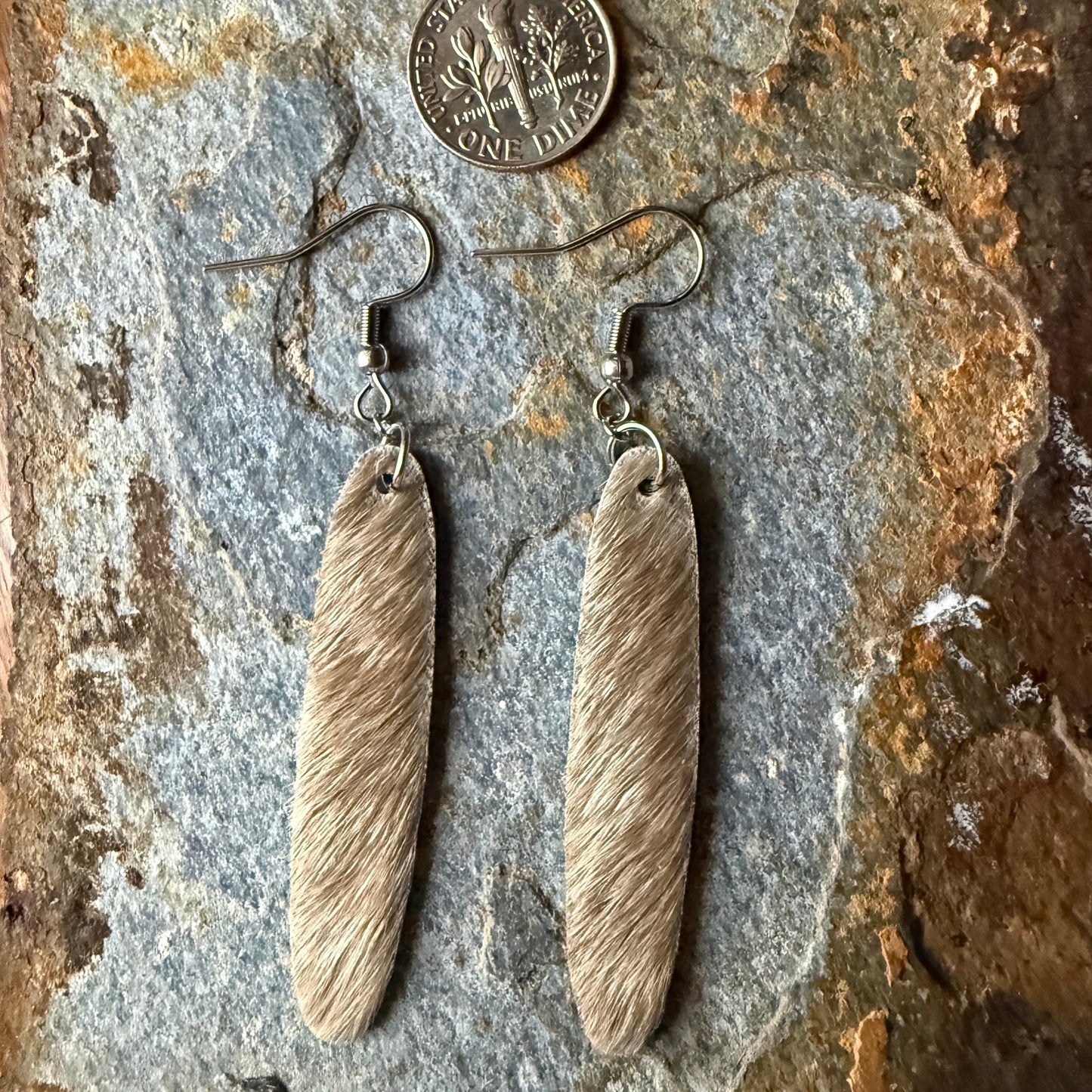 Cowhide oval shaped earrings on a stone surface