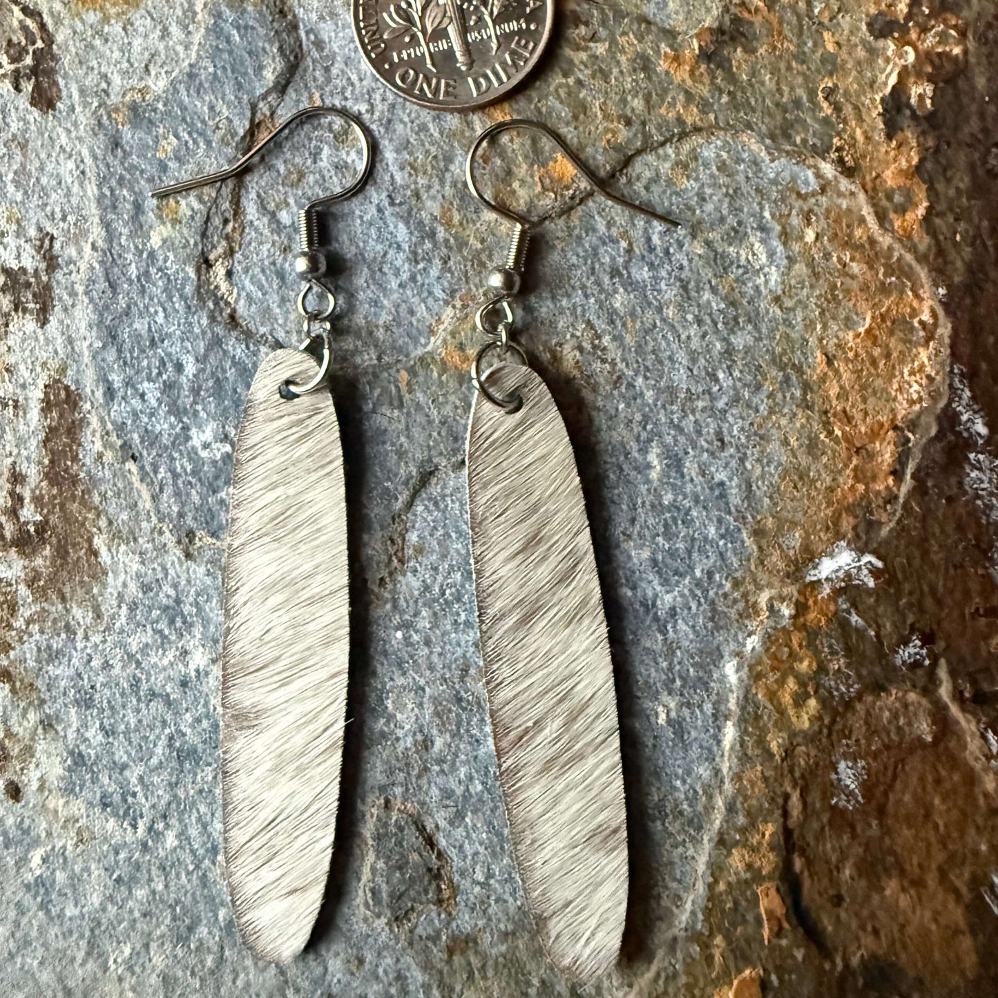 Cowhide oval shaped earrings on a stone surface