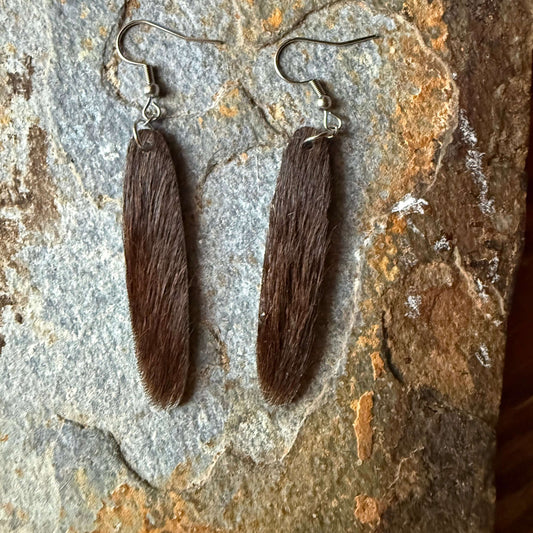Cowhide oval shaped earrings on a stone surface