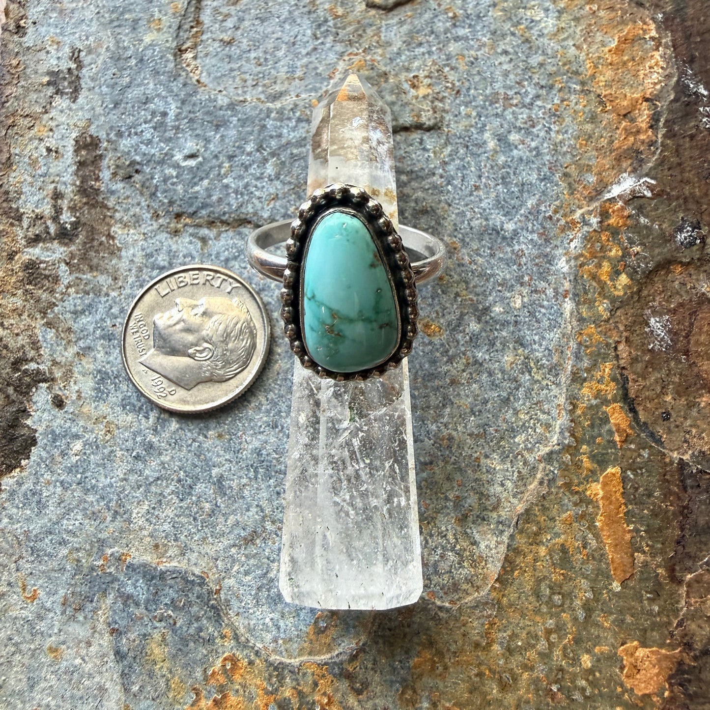 Turquoise ring on a rock with a coin for scale