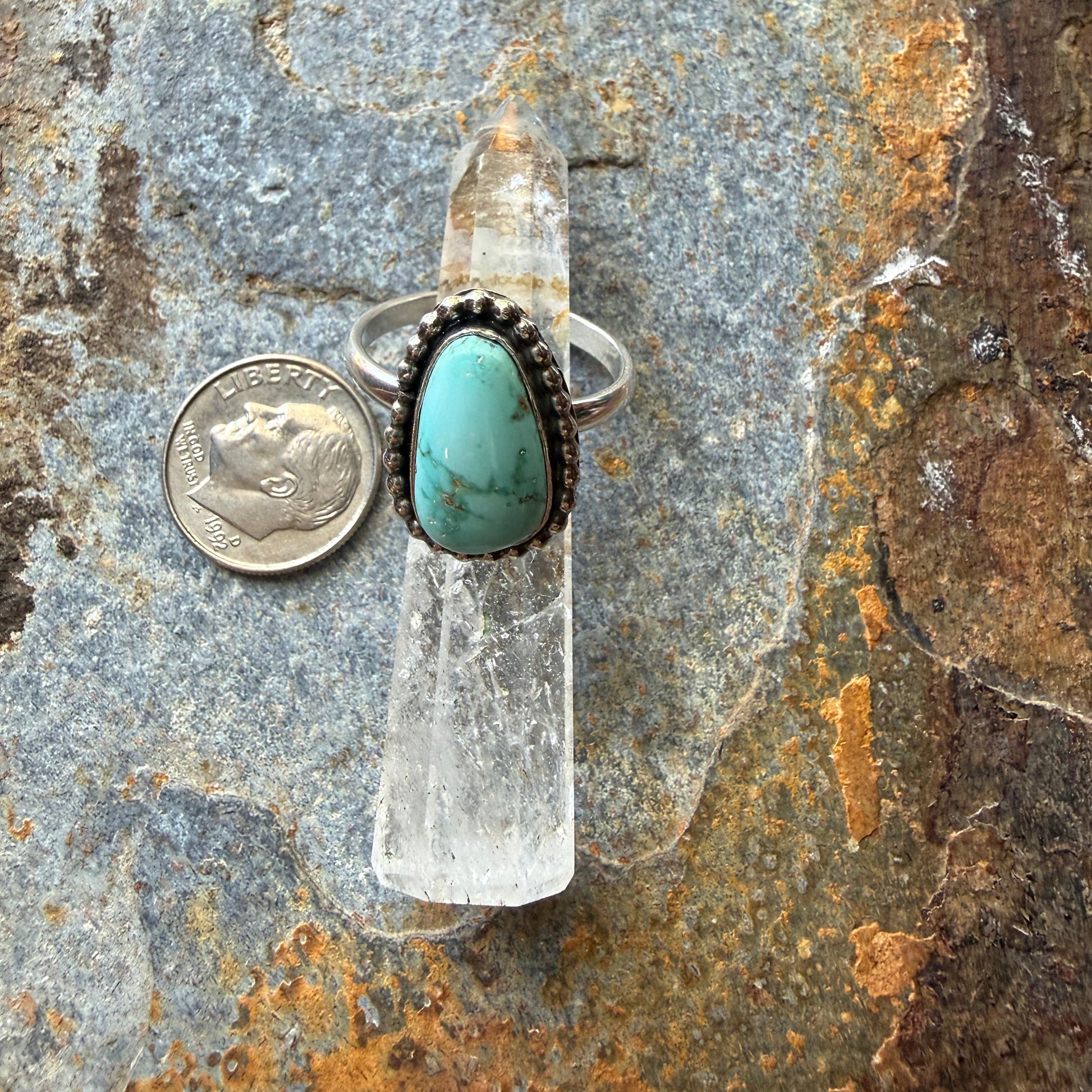 Turquoise ring on a rock with a coin for scale