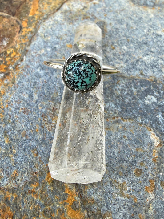 Crystal with a dark green druzy top on a textured stone surface