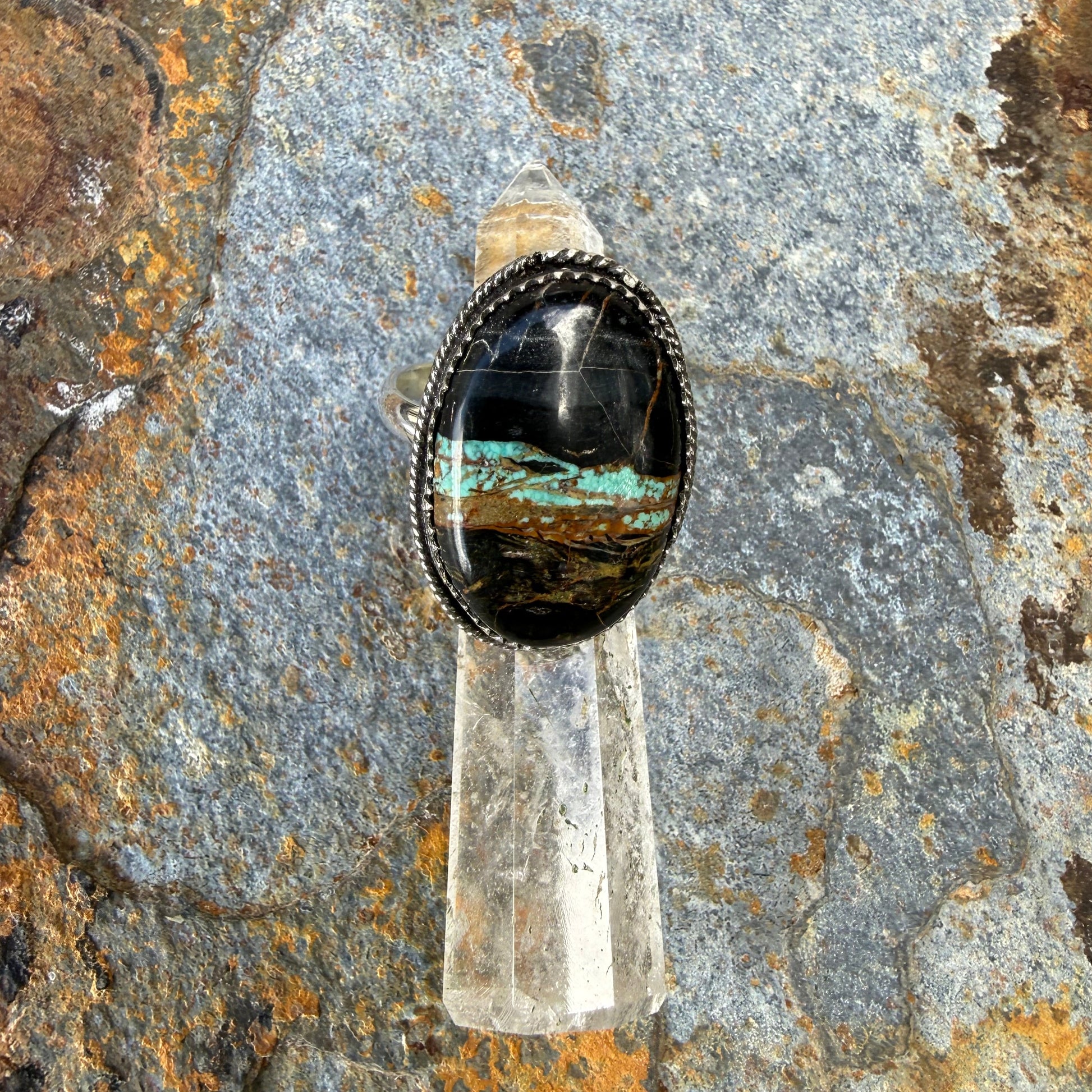 BLACK JACK TURQUOISE STERLING SILVER RING ON A STONE SURFACE