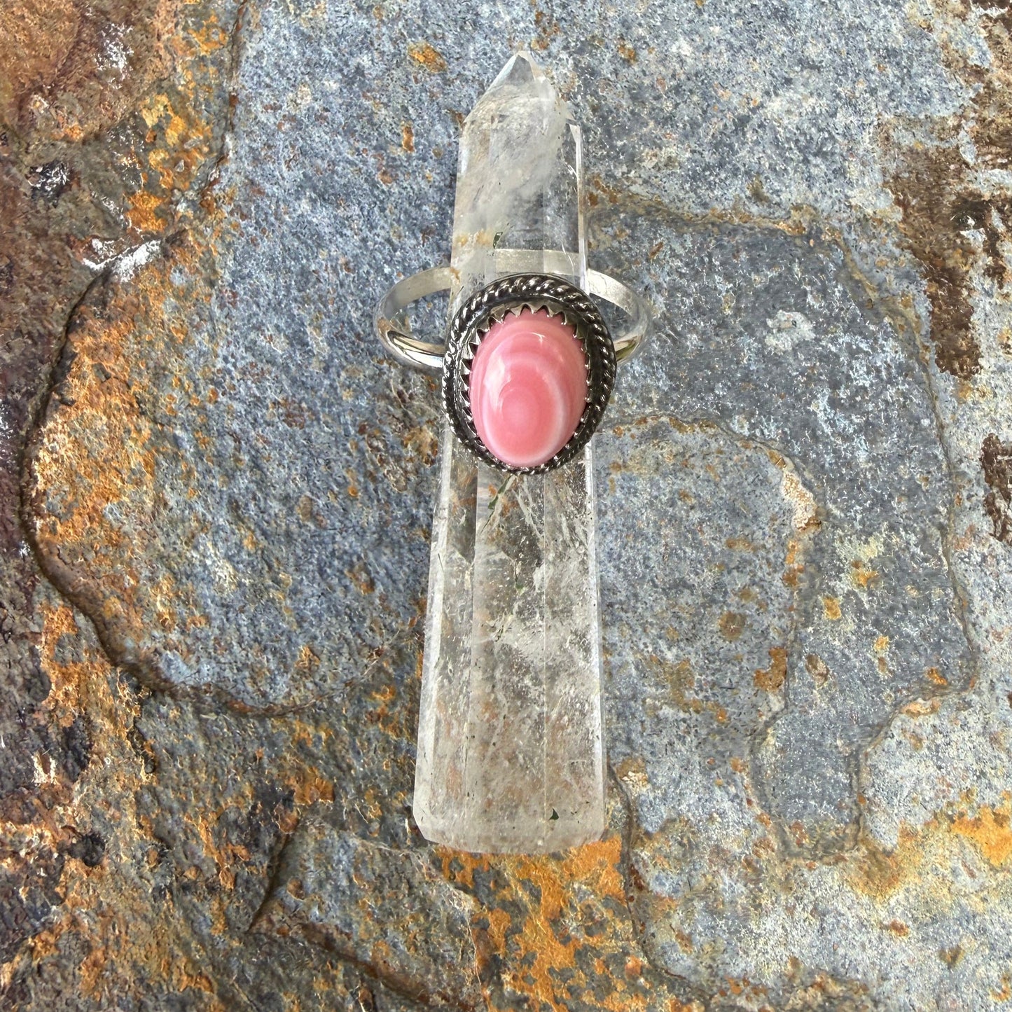 Clear crystal pendant with pink stone on a rusted stone surface