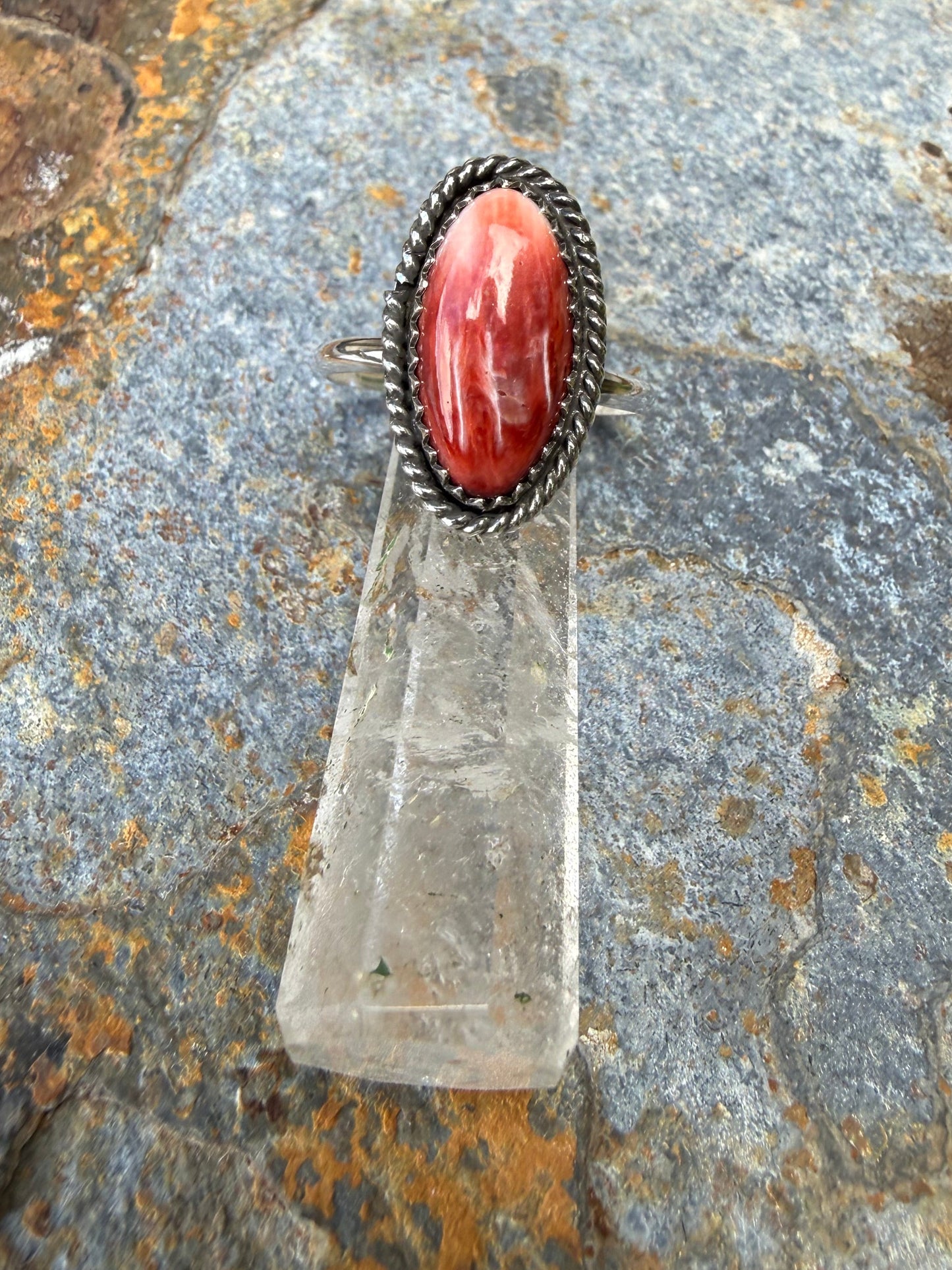 Silver ring with a red stone on a textured rock background