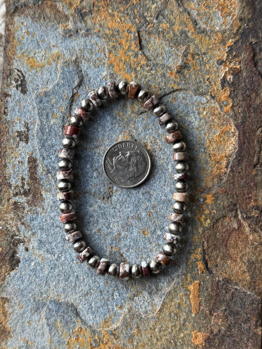 Beaded bracelet on a textured stone surface with a coin for scale